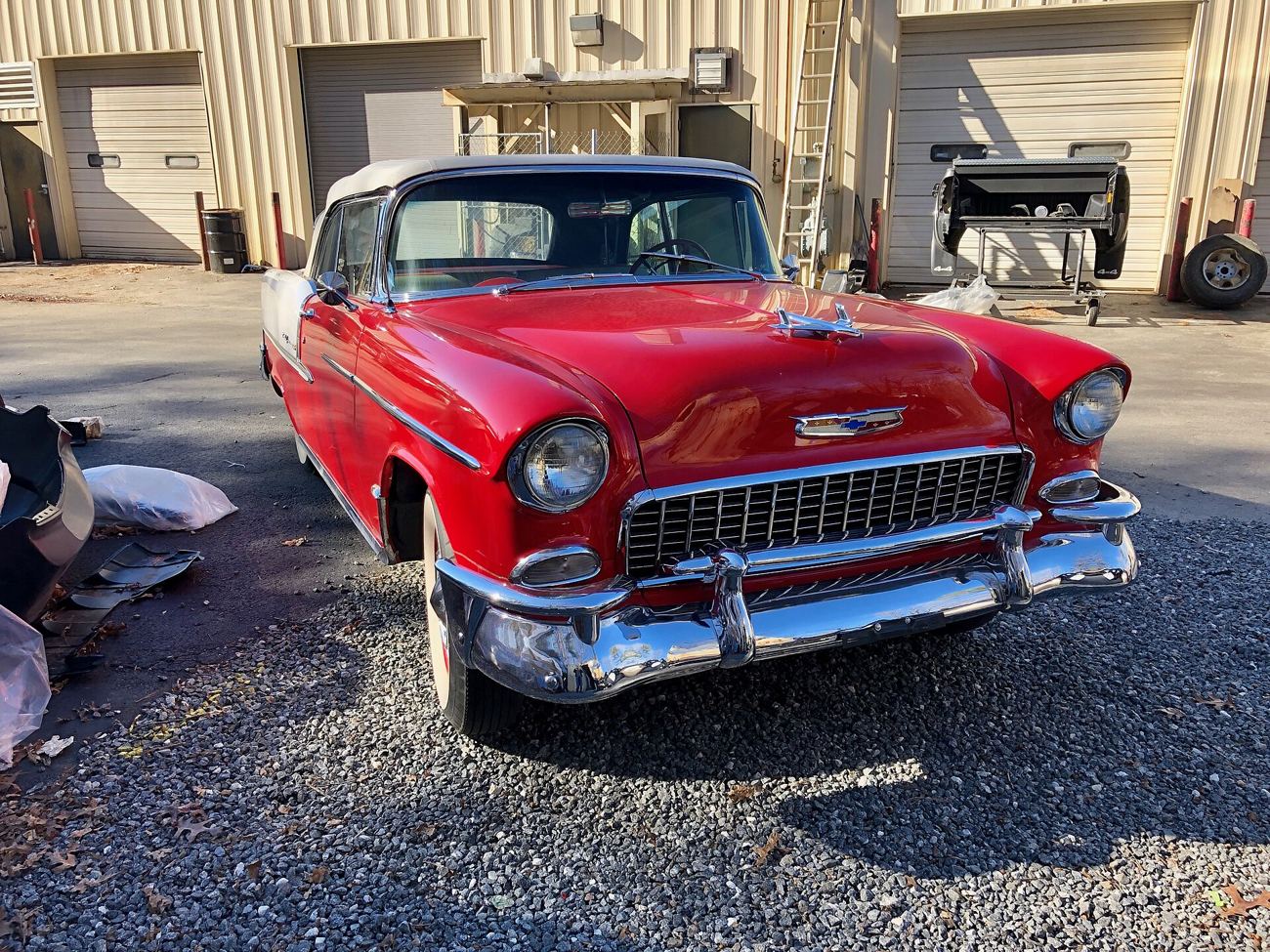 Röd och vit Chevrolet Bel Air från 1955 med kromgrill och vitsidiga däck
